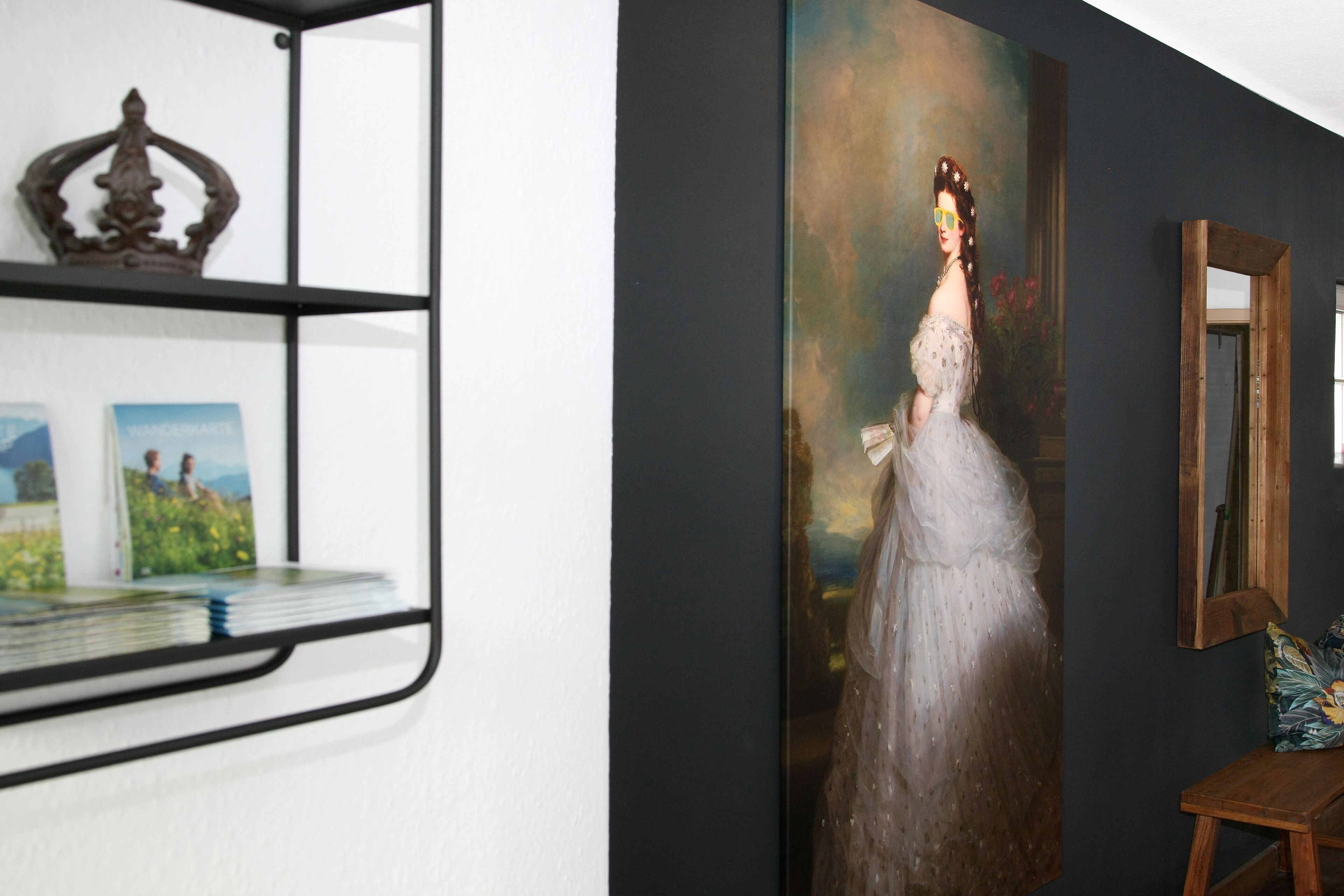 A room with a large portrait painting, a wooden shelf with decorative items, and a mirror on the wall.