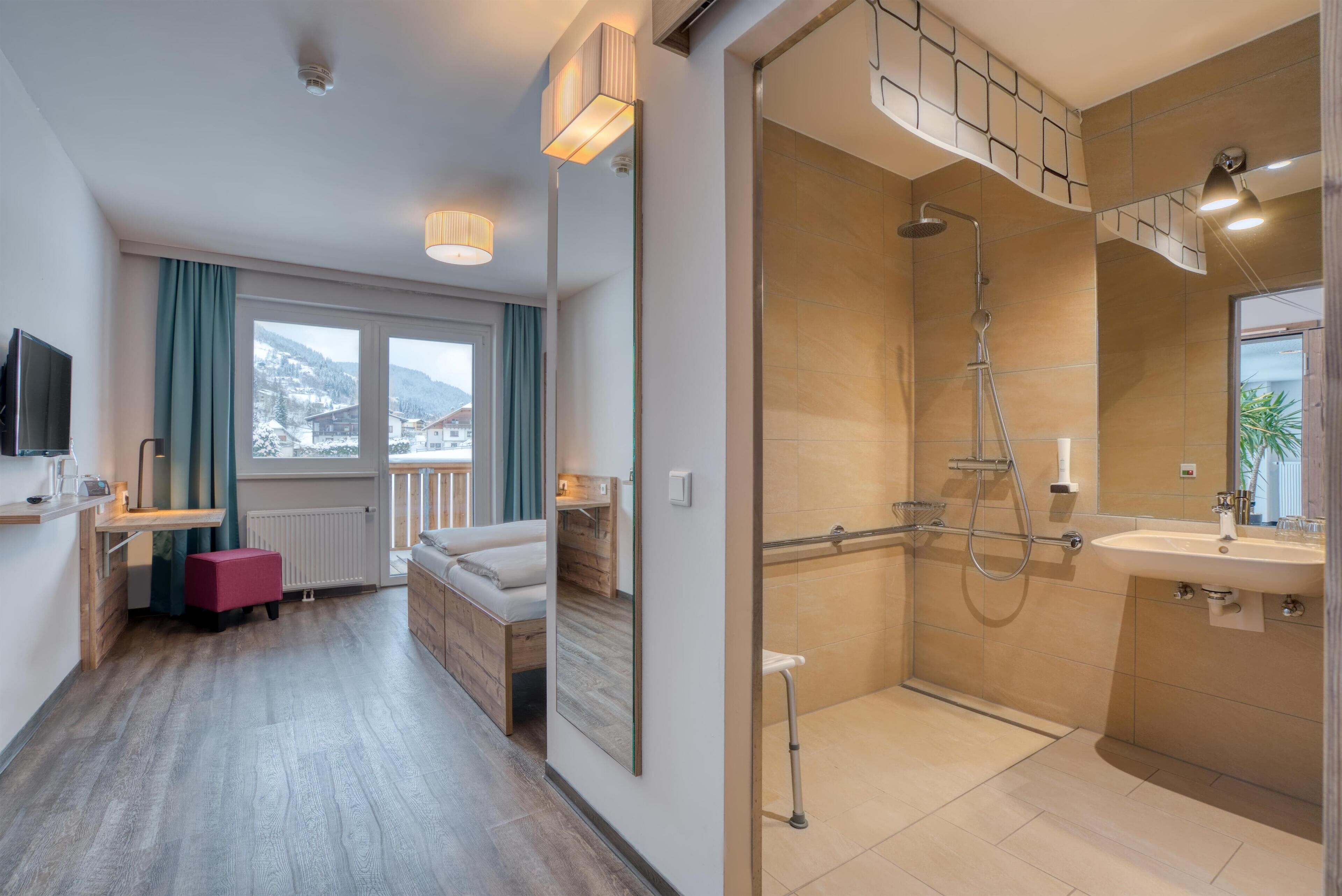 A modern bathroom with a shower, sink, and large mirror. There is a window with a view of the mountains.