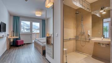 A modern bathroom with a shower, sink, and large mirror. There is a window with a view of the mountains.