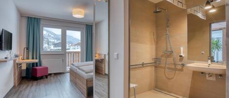 A modern bathroom with a shower, sink, and large mirror. There is a window with a view of the mountains.