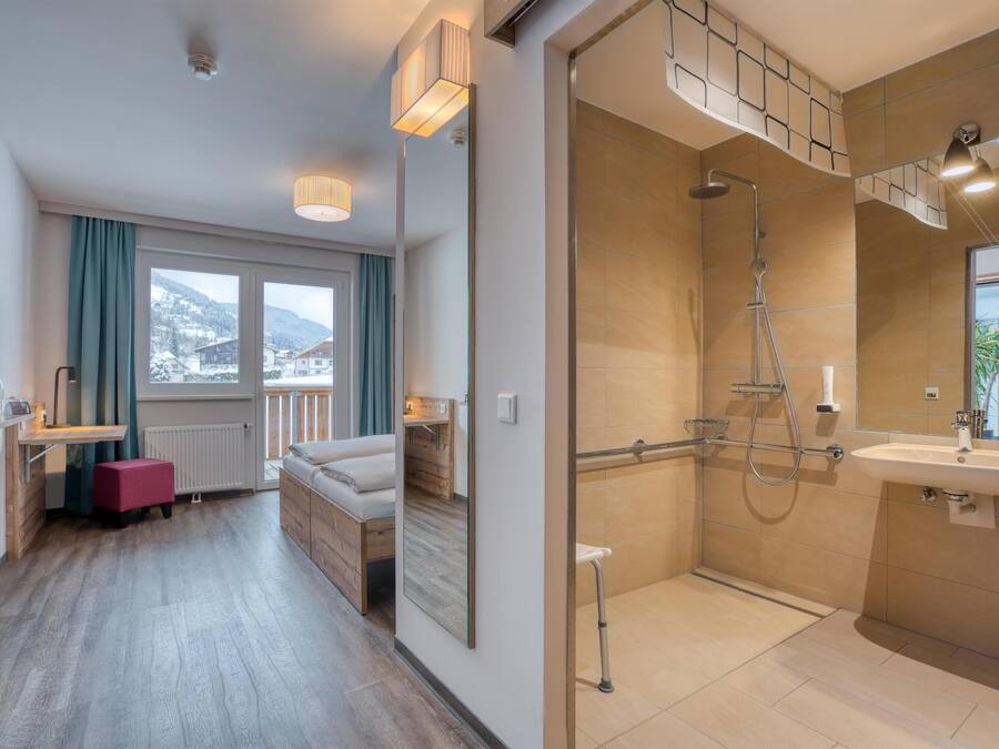 A modern bathroom with a shower, sink, and large mirror. There is a window with a view of the mountains.