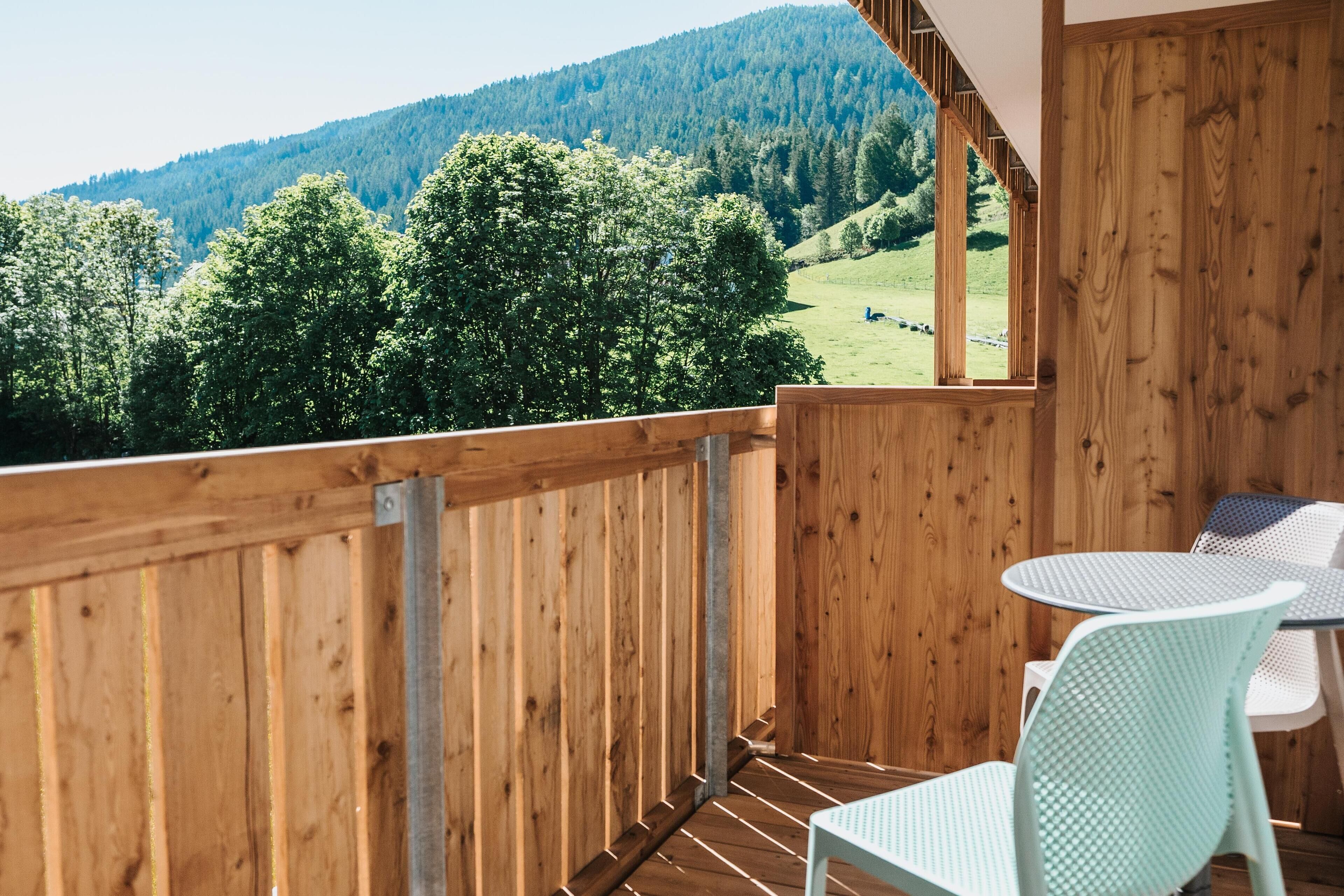 A wooden deck with a view of a green landscape and a mountain in the background.