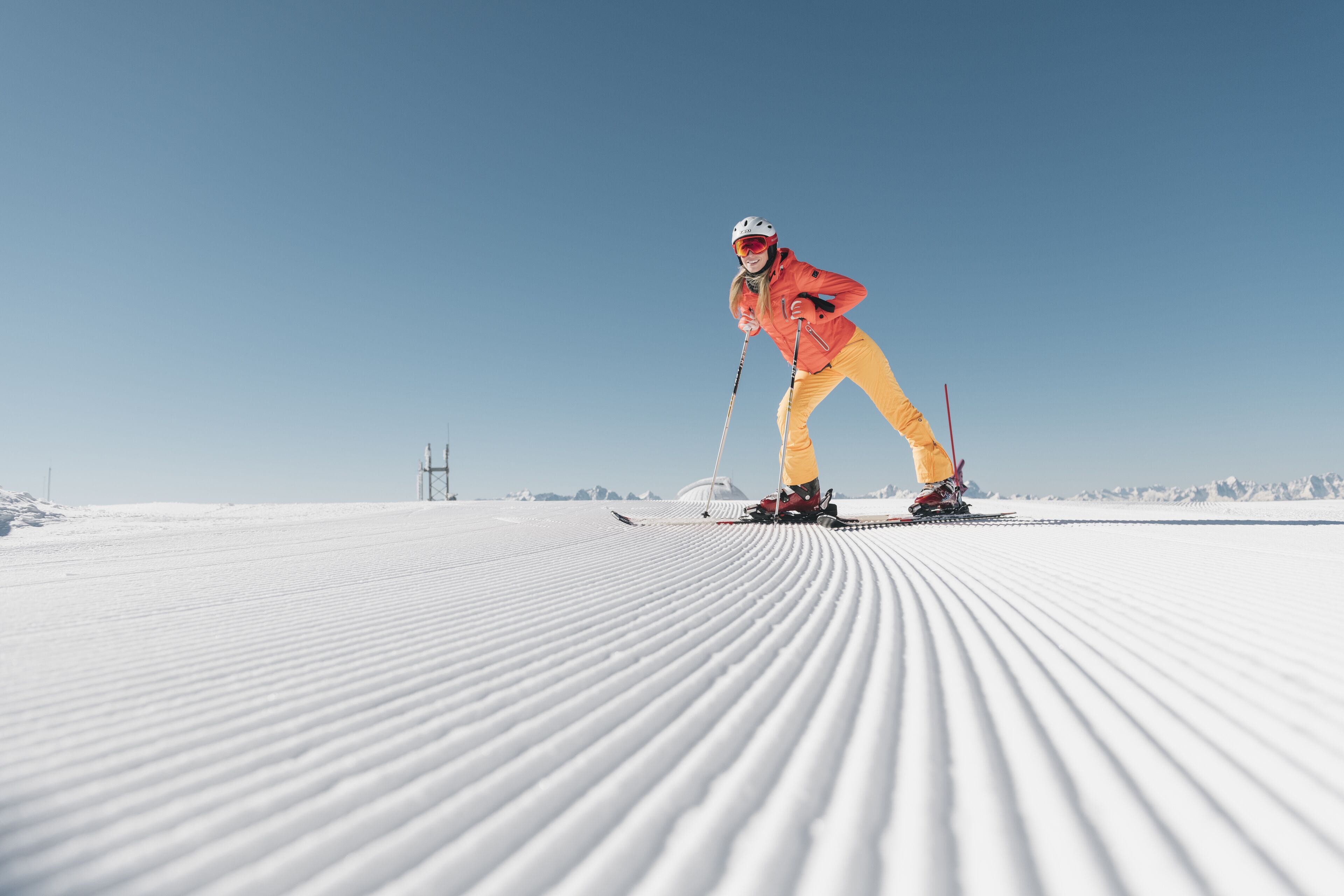 Una persona esquiando en una pendiente cubierta de nieve bajo un cielo despejado.