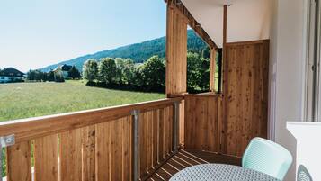 Ein Holzbalkon mit Blick auf ein grünes Feld und Berge.