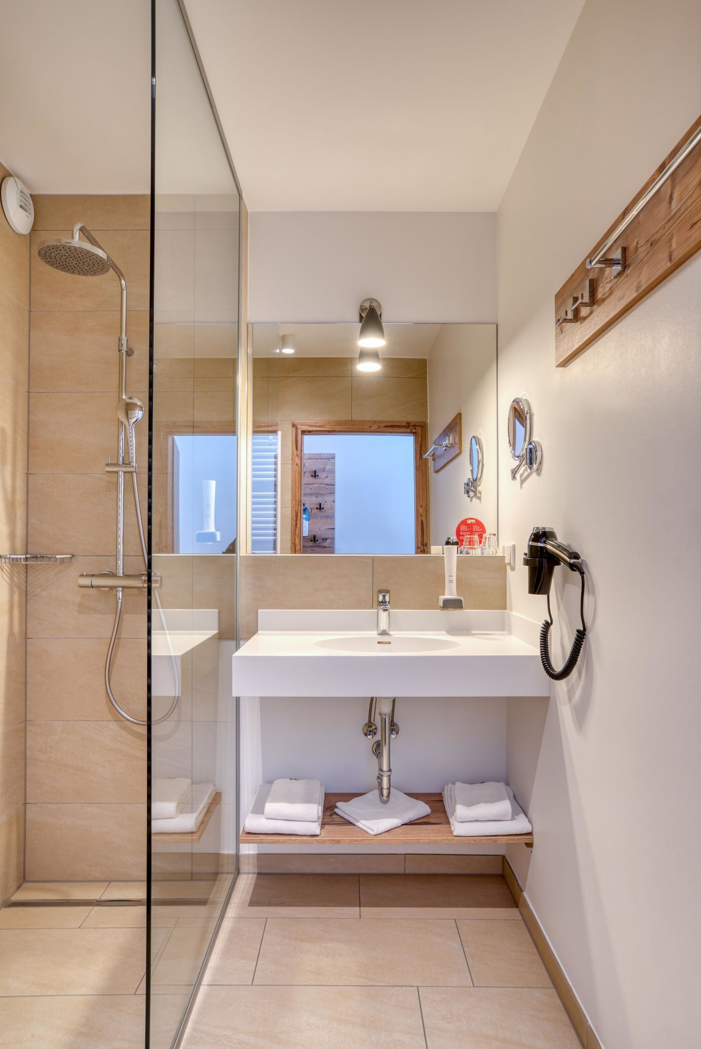 Un baño moderno con cabina de ducha de vidrio, un lavabo blanco y un espejo.