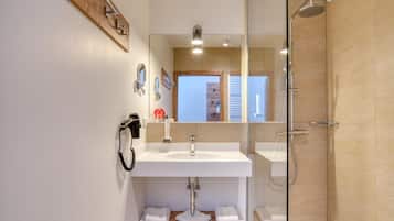 Een moderne badkamer met een witte wastafel, een douchecabine van glas en een houten wastafelmeubel.