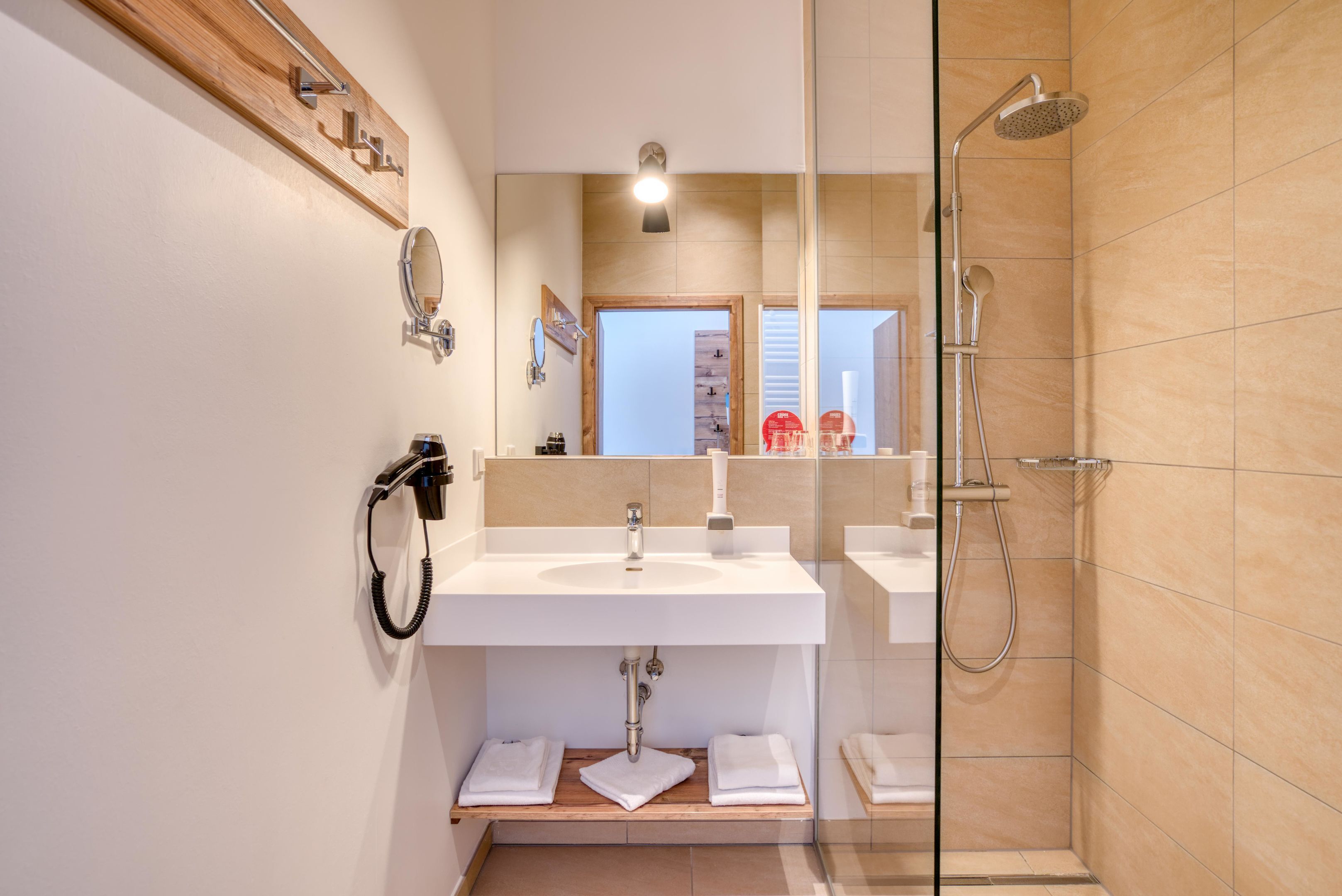 A modern bathroom with a glass shower enclosure, a wooden vanity, and a mirror above the sink.