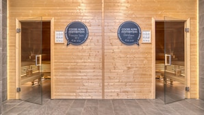 A wooden sauna with glass doors, labeled COOEE ALPIN, and a temperature of 55°C. - COOEE alpin Hotel Bad Kleinkirchheim (Bad Kleinkirchheim)