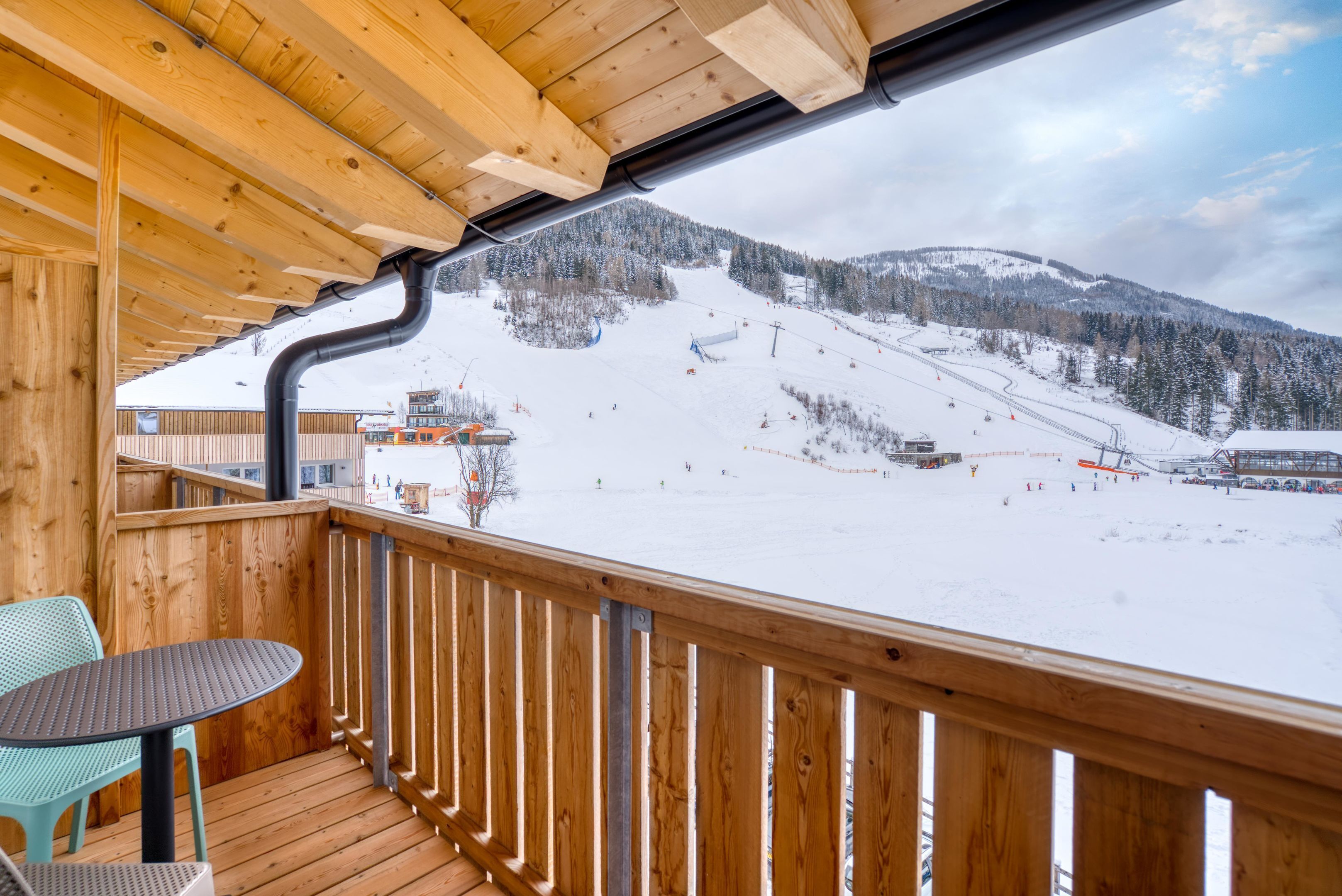 A wooden deck with a view of a snowy mountain slope.
