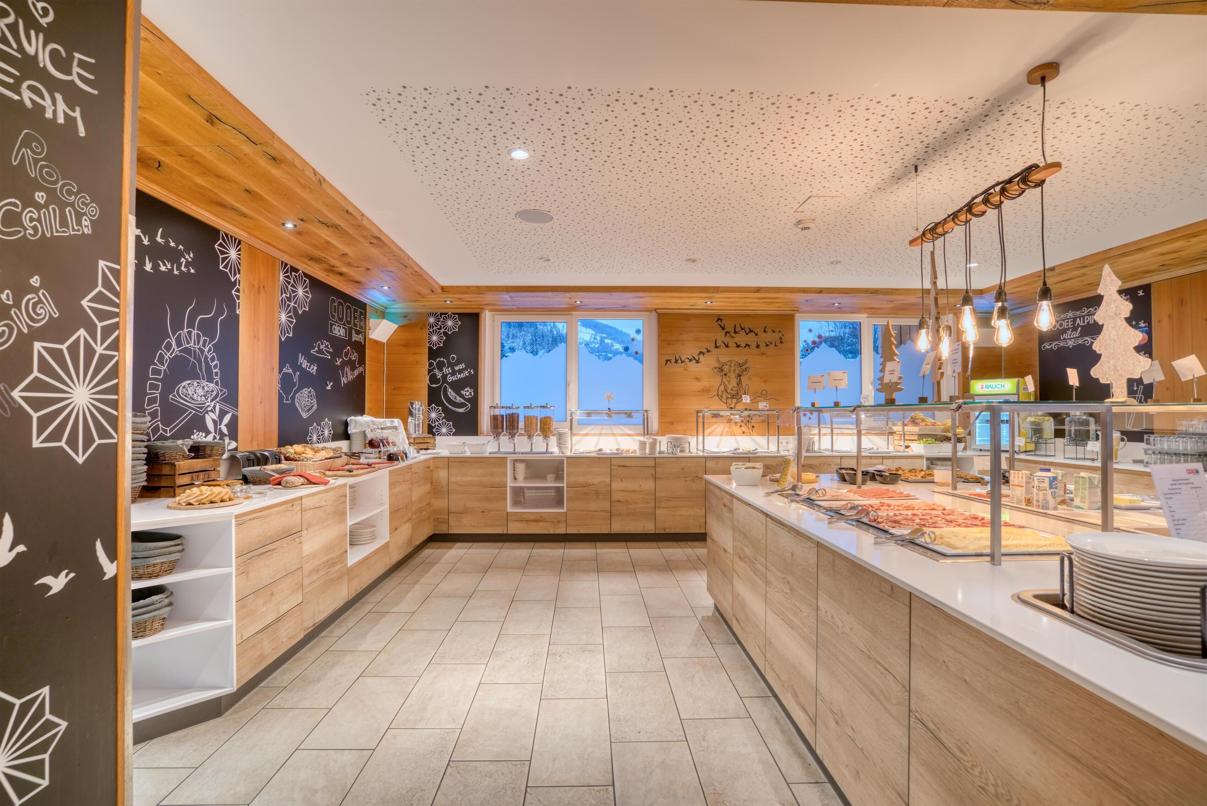 A modern breakfast area with wooden cabinets, a chalkboard wall with menu items, and a view of the outdoors.