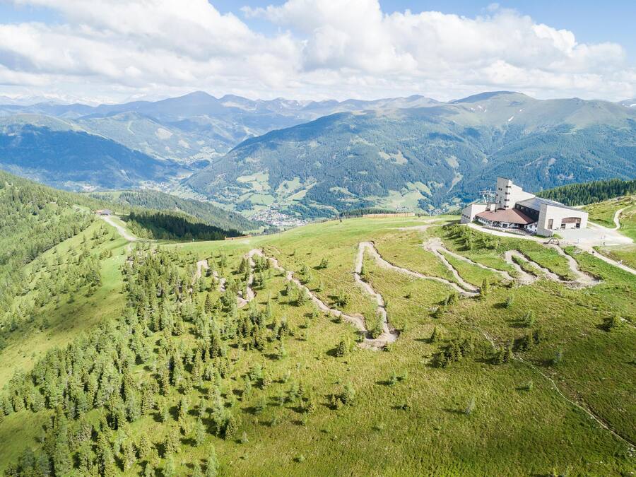 A building with a modern architectural style, surrounded by a lush green landscape and mountains in the background.