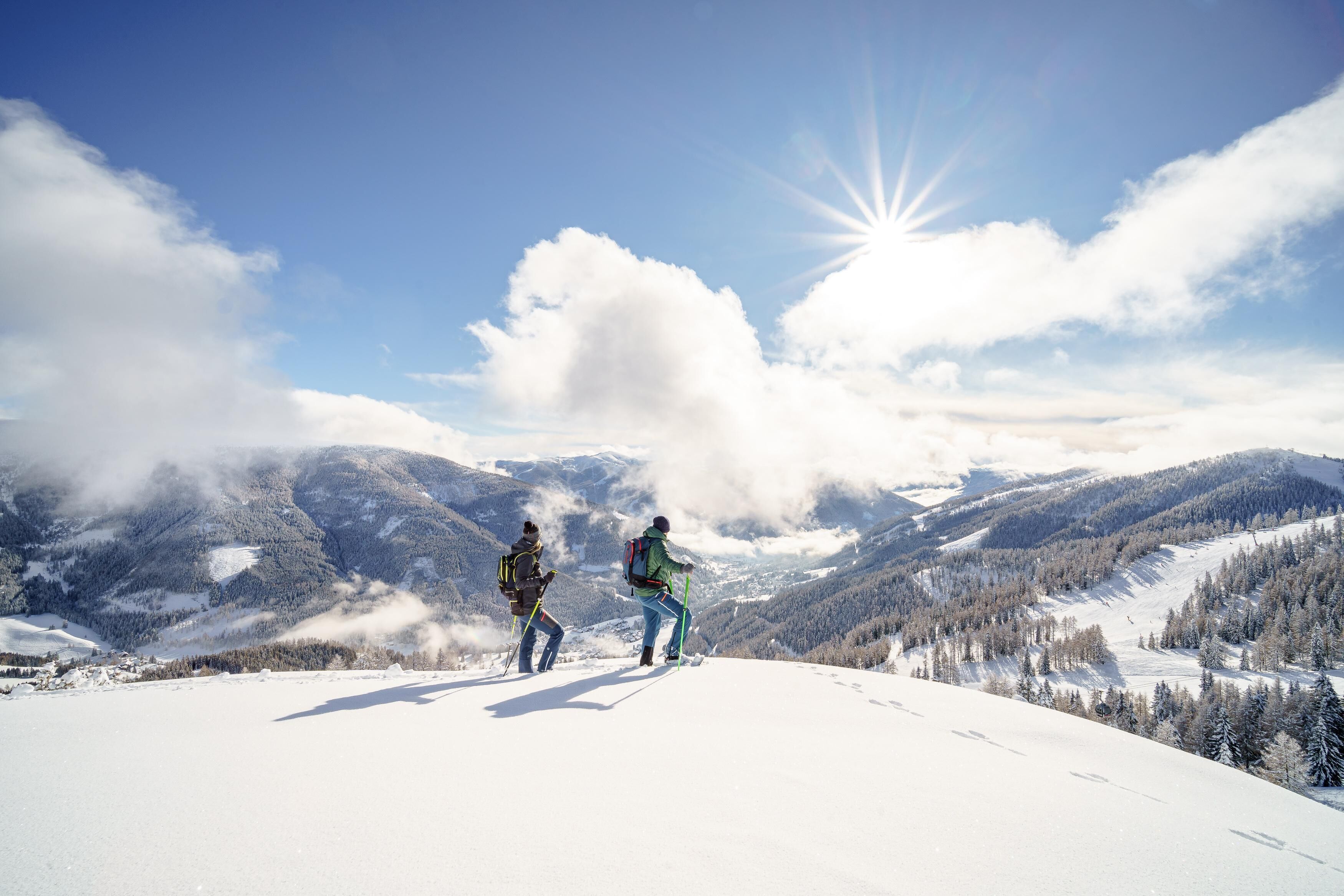 A snowy mountain landscape with two people hiking.