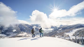 Un paysage de montagne enneigé où l’on voit deux personnes en randonnée.