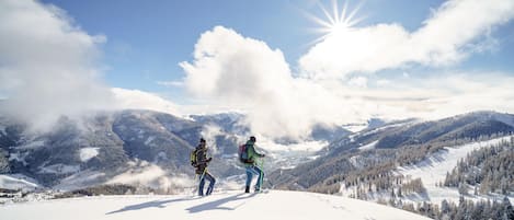 A snowy mountain landscape with two people hiking.