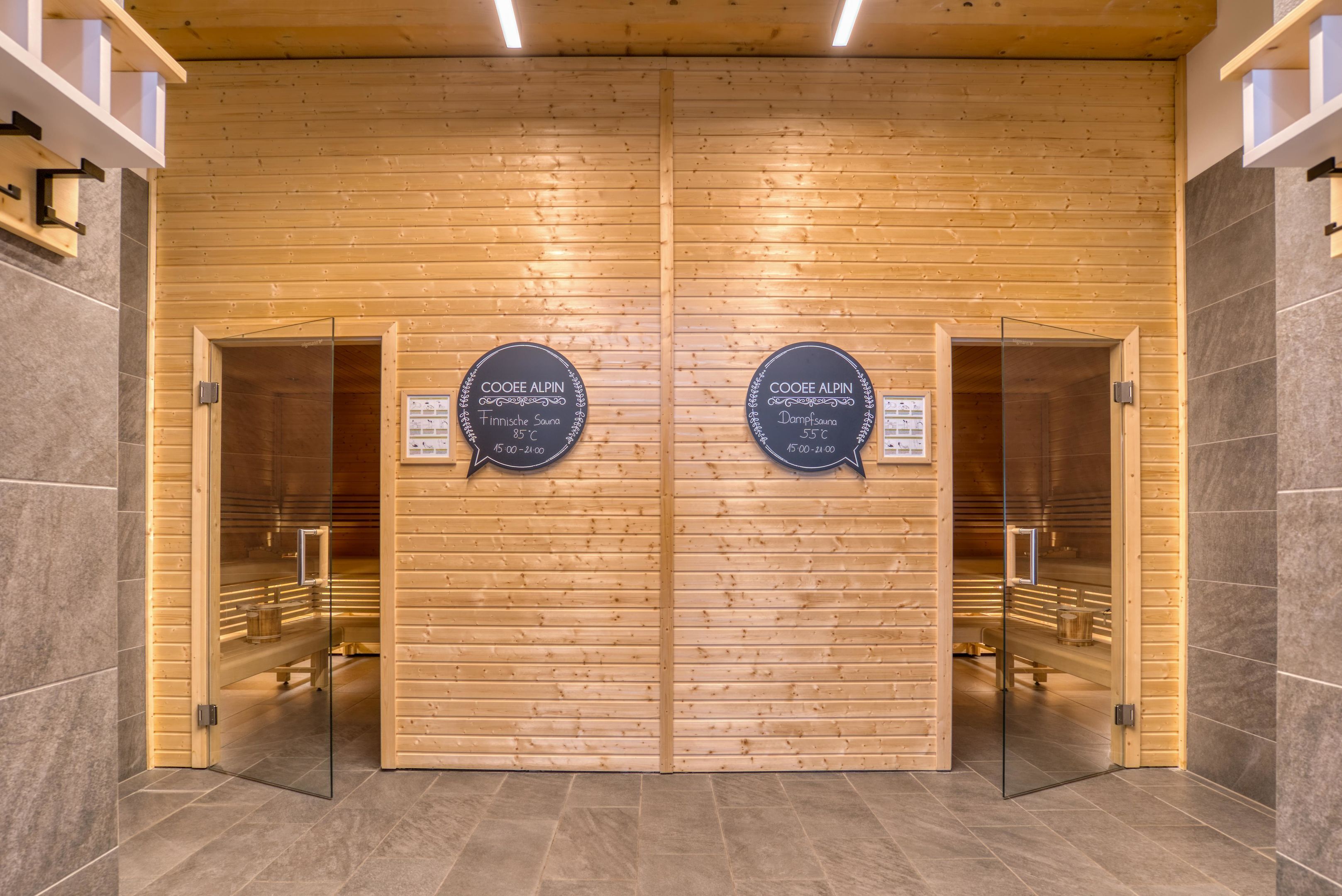 A wooden wall with two doors labeled 'COOEE ALPIN' and 'Finstra Sauna' with a temperature of 85°C.