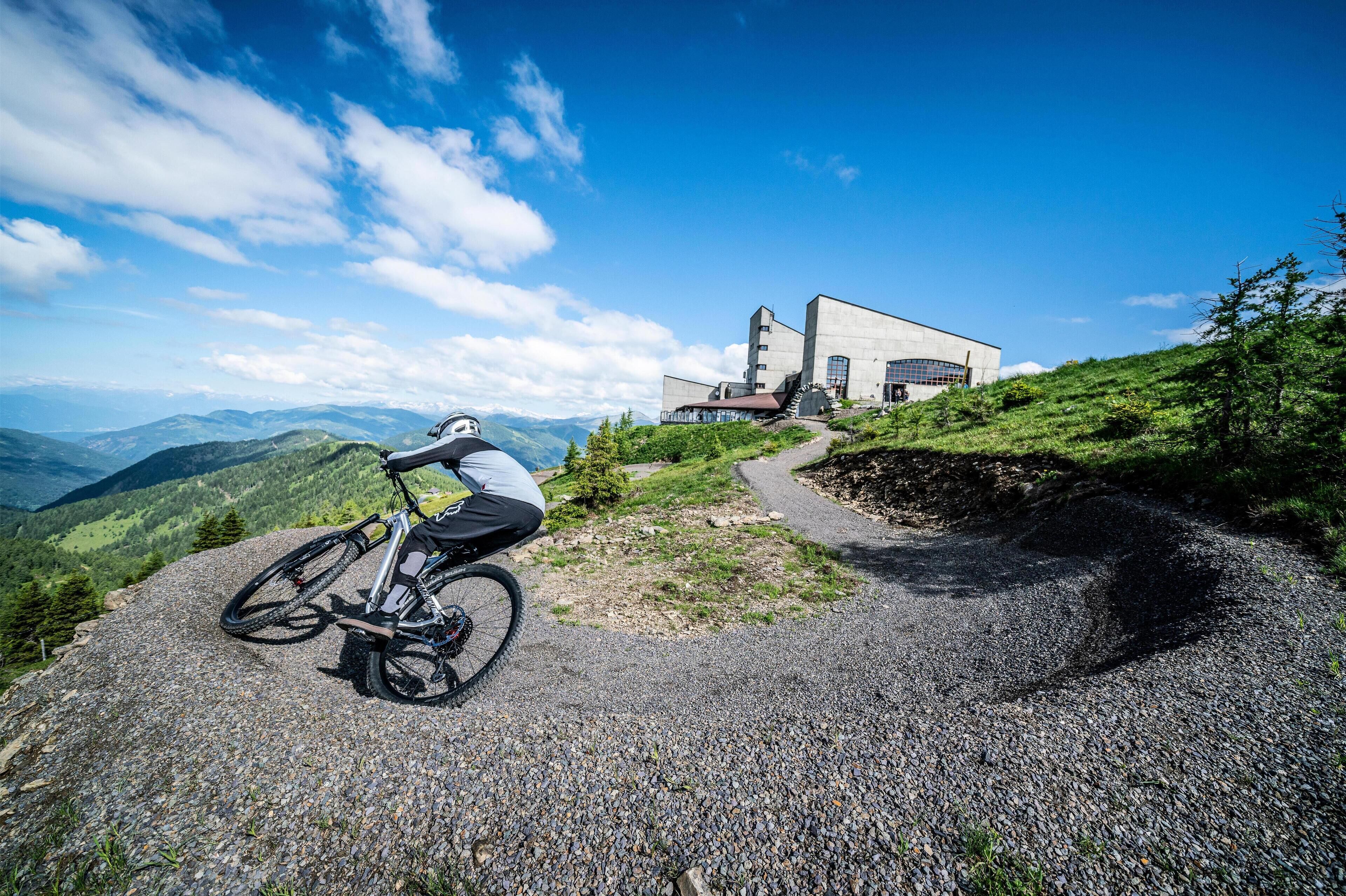 A mountain bike on a gravel path with a modern building in the background.