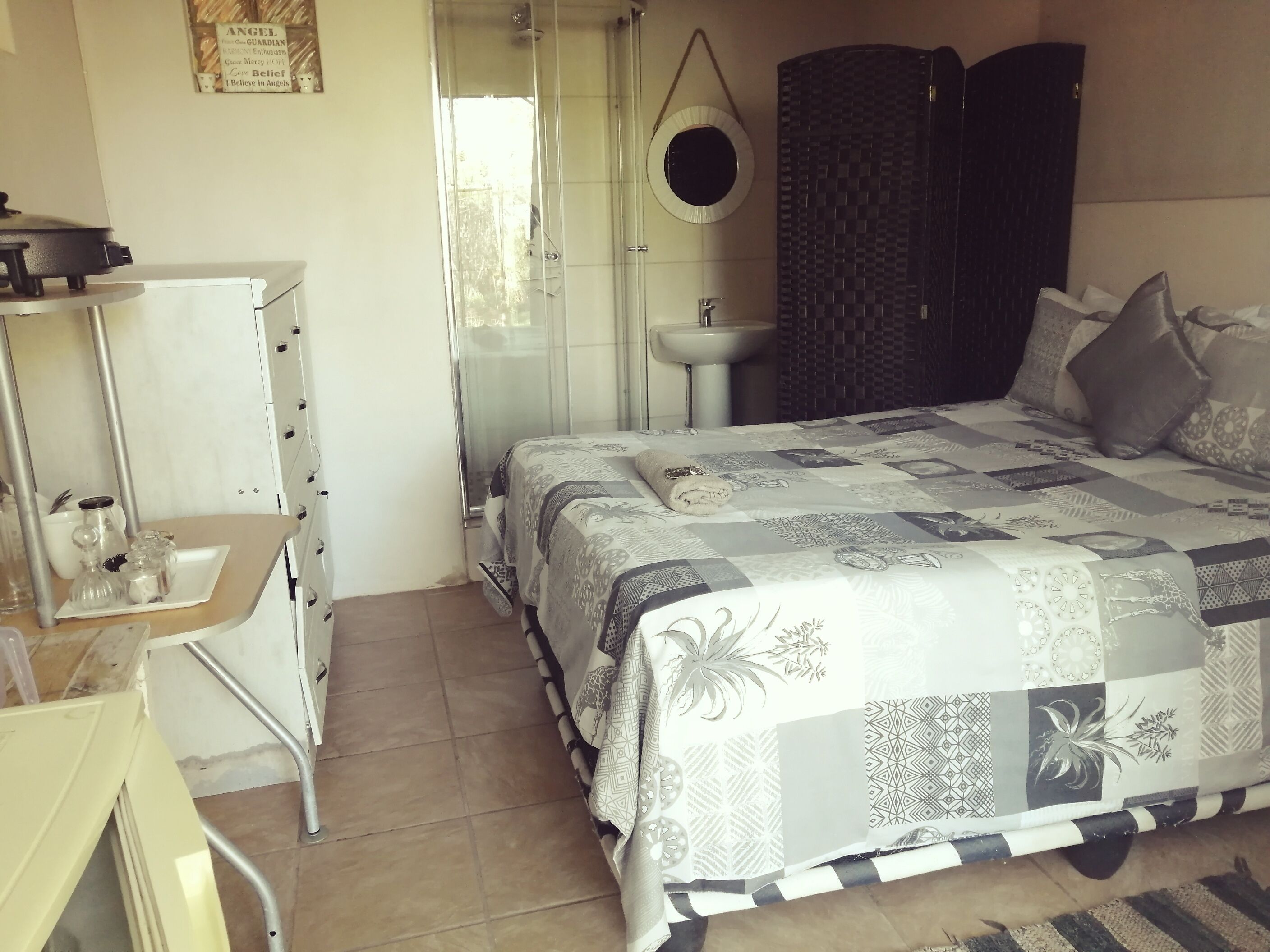 Un dormitorio con cama, escritorio, silla, lavamanos y ducha.