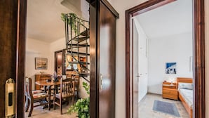 Una habitación con comedor, escalera, cama y mesita de noche.
