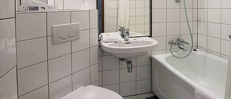 A modern bathroom with a toilet, sink, and bathtub.