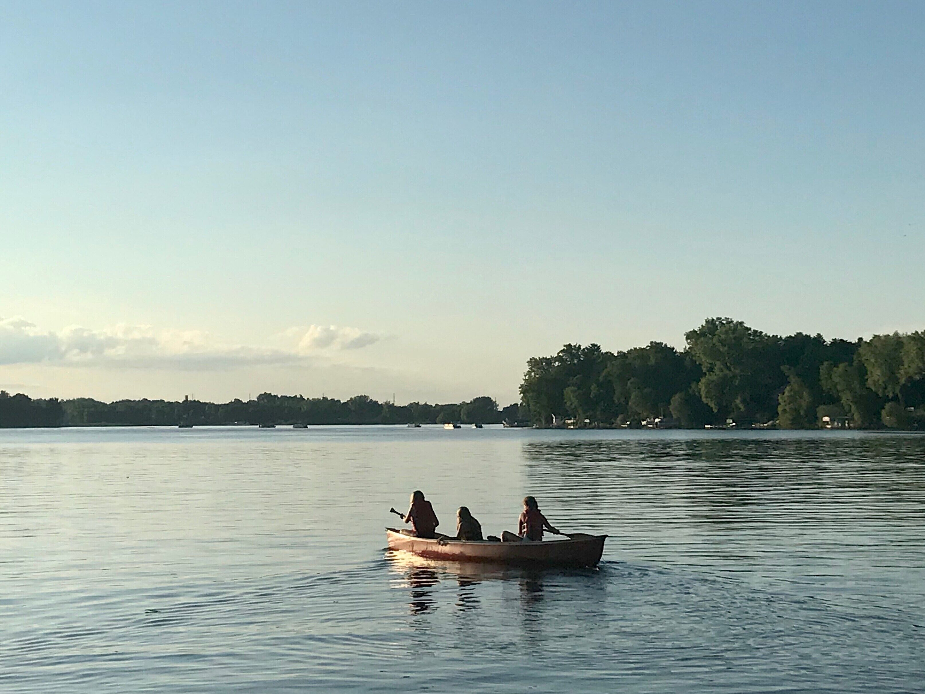 Un lago tranquilo con un bote pequeño que lleva a tres personas.