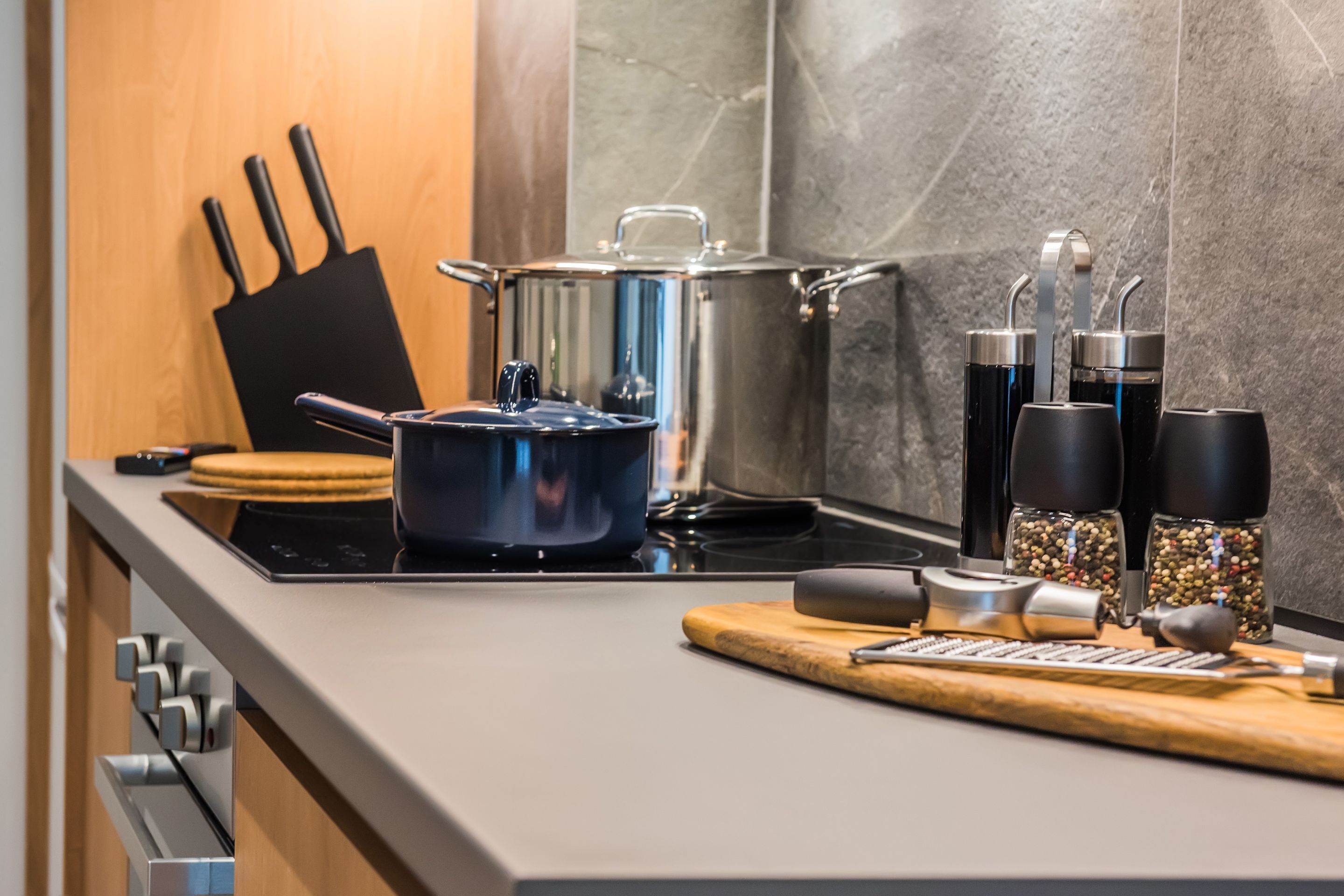 A modern kitchen with a stove, pots, a cutting board, and various kitchen utensils.