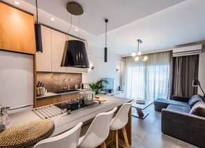 A modern kitchen with a central island, white chairs, and a dining table. - Nereids Apts by halu! Apartments (Thessaloniki)