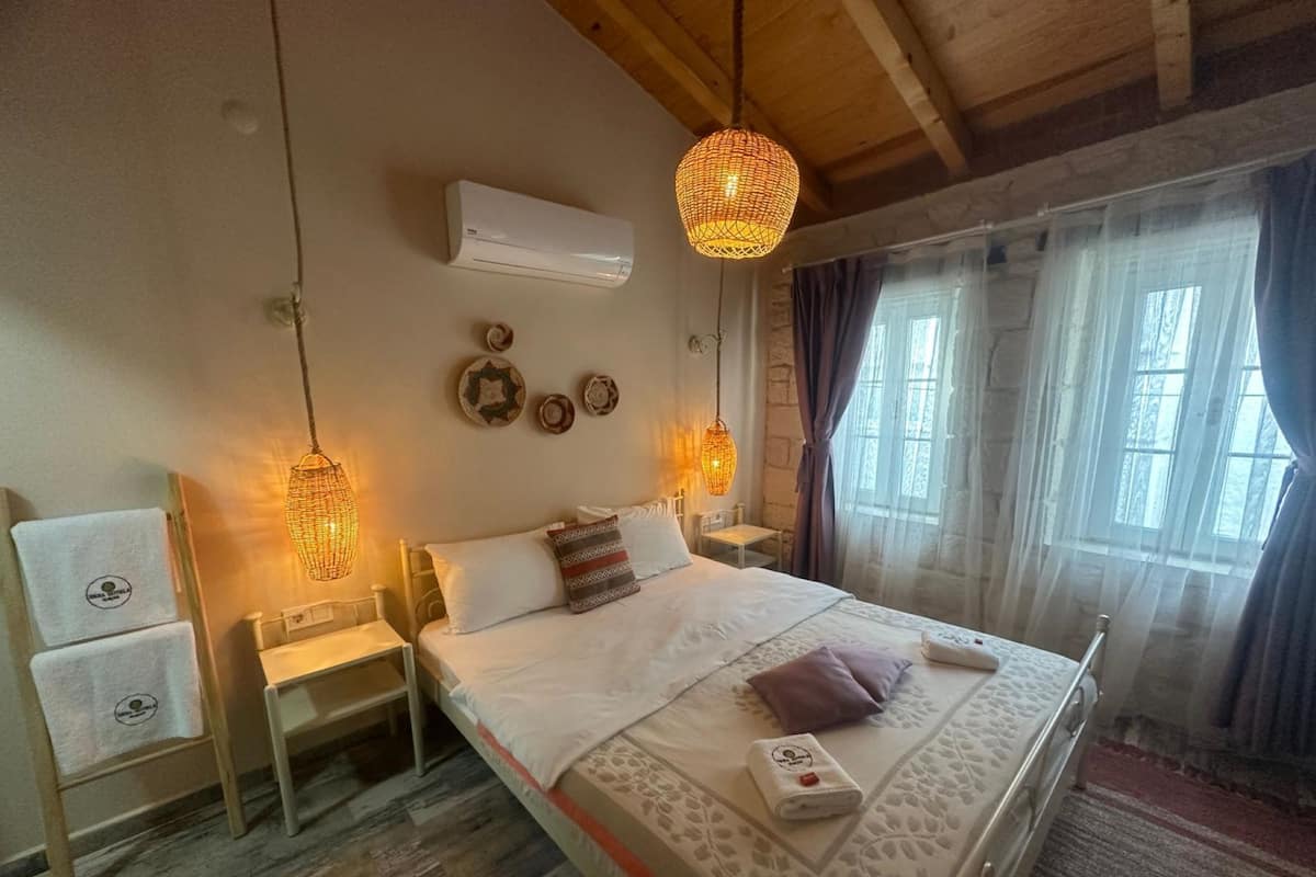 Un dormitorio con cama, mesitas de noche, aire acondicionado, paneles decorativos en la pared y una ventana con cortinas.