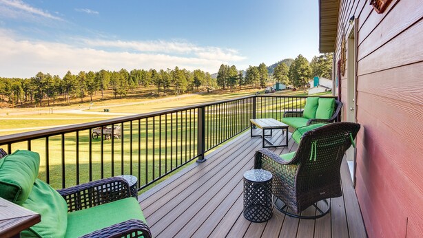 Une terrasse en bois, meublée de meubles en osier, avec vue sur un terrain de golf.