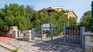 A gated entrance with a stone pathway leading to a building with a tiled roof.