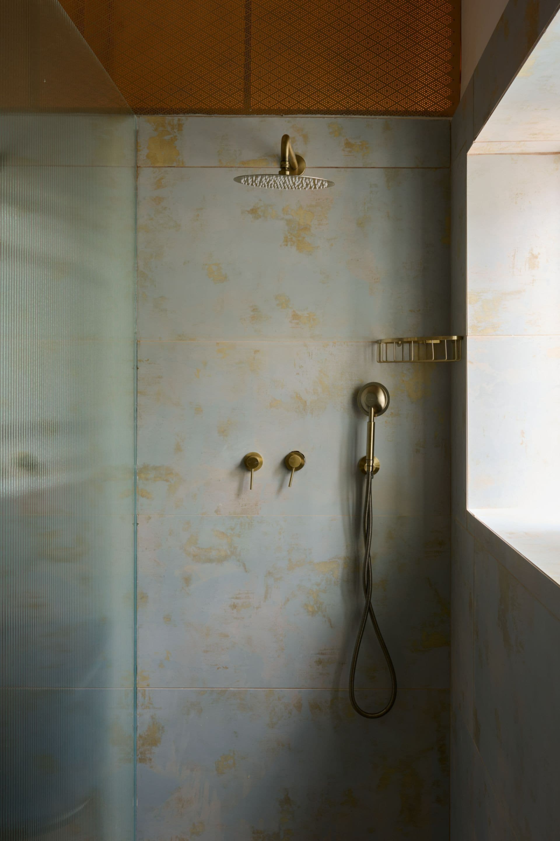 A shower with a handheld showerhead, a wall-mounted faucet, and a handheld showerhead.
