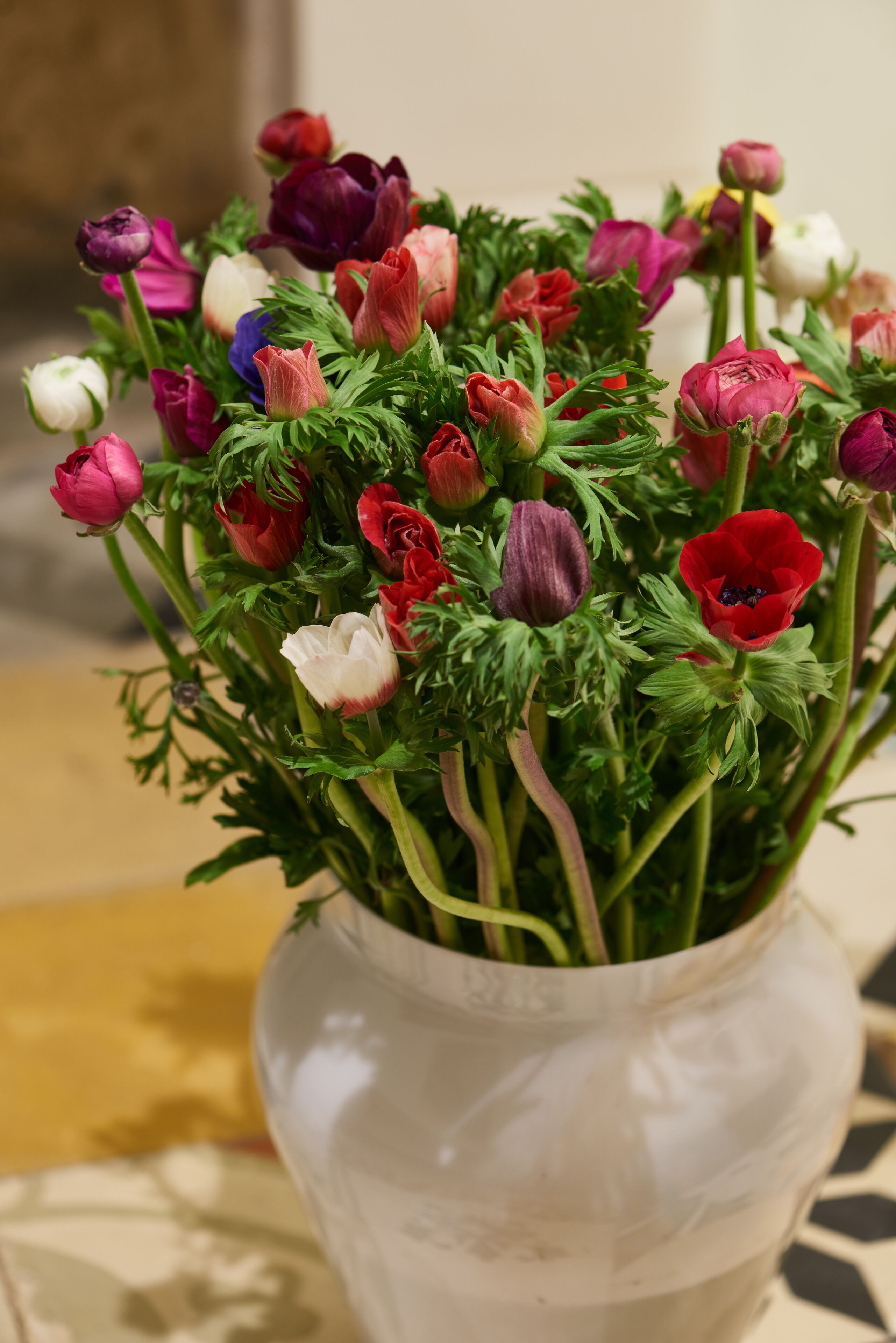 A white vase with a bouquet of tulips in various colors.
