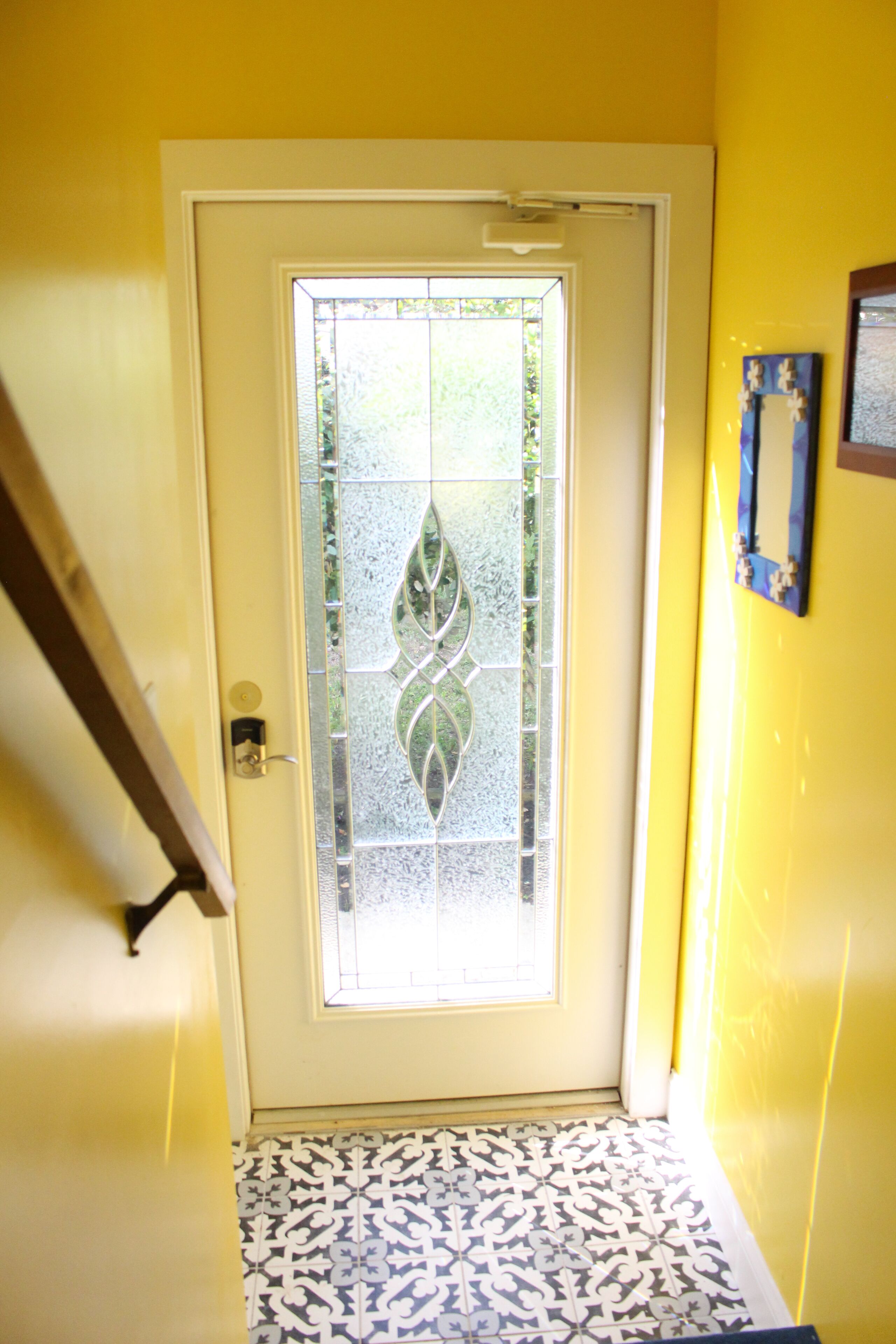 A door with a frosted glass panel and a patterned tile floor.