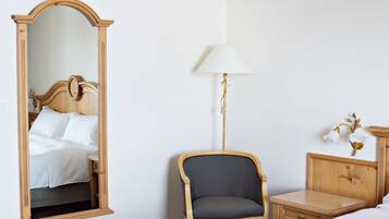 Un dormitorio con una cama de madera, un espejo, una silla, una mesita de noche y una lámpara.