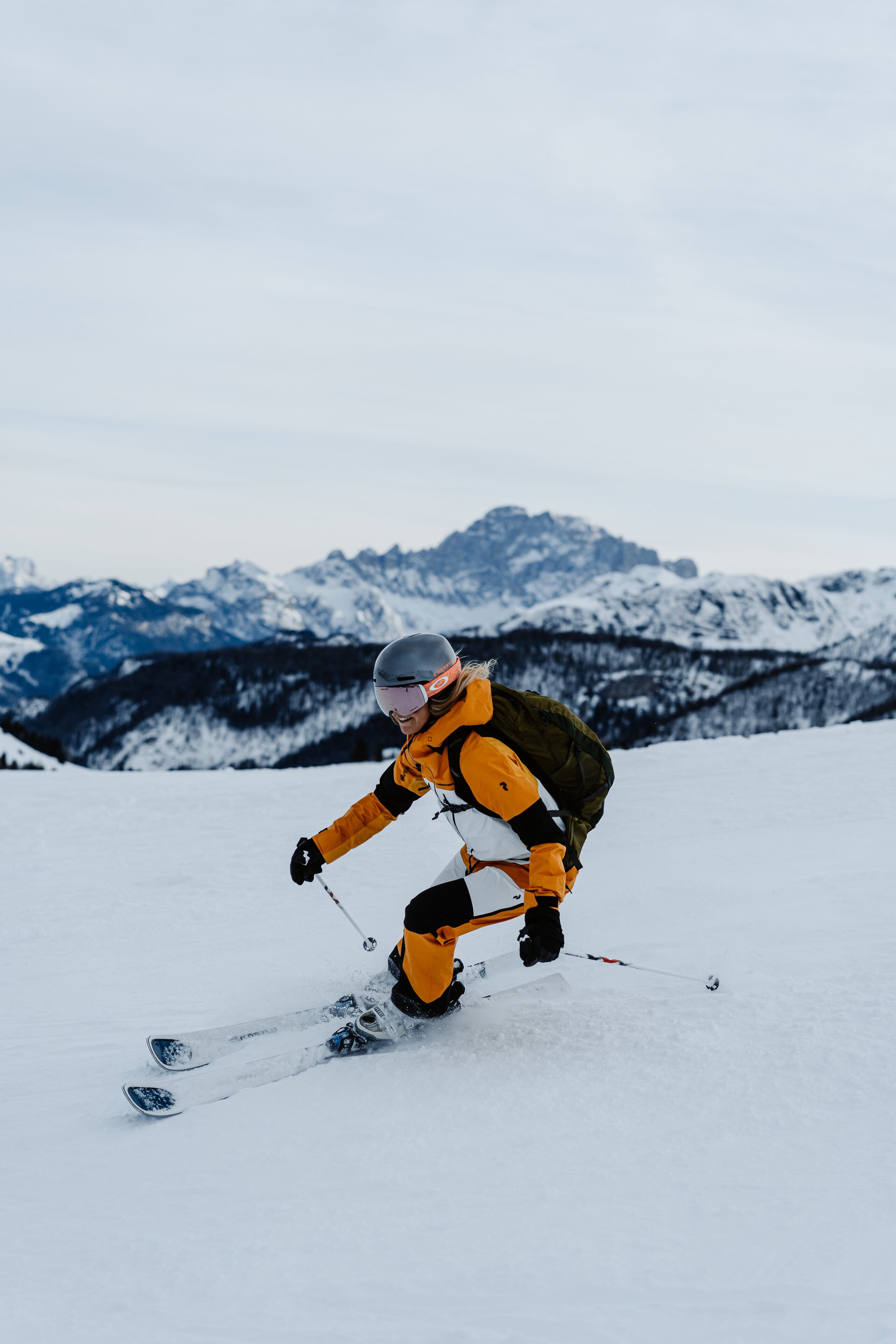A person skiing on a snowy slope with mountains in the background.