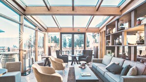 A modern interior with a glass ceiling, seating area, and shelves with decorative items. - Paradiso Pure.Living Vegan Hotel (Castelrotto)