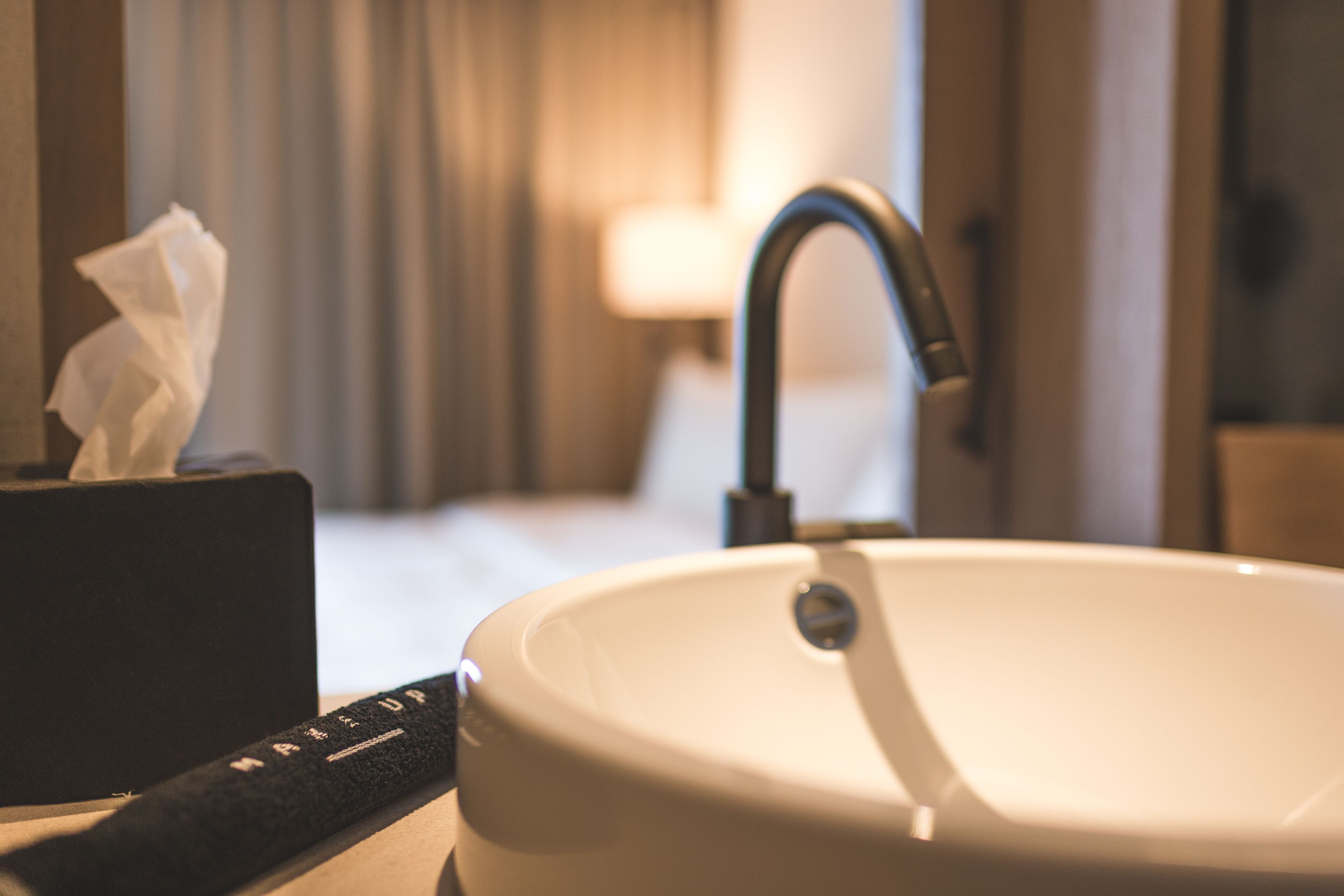 A bathroom sink with a tissue box and a faucet.