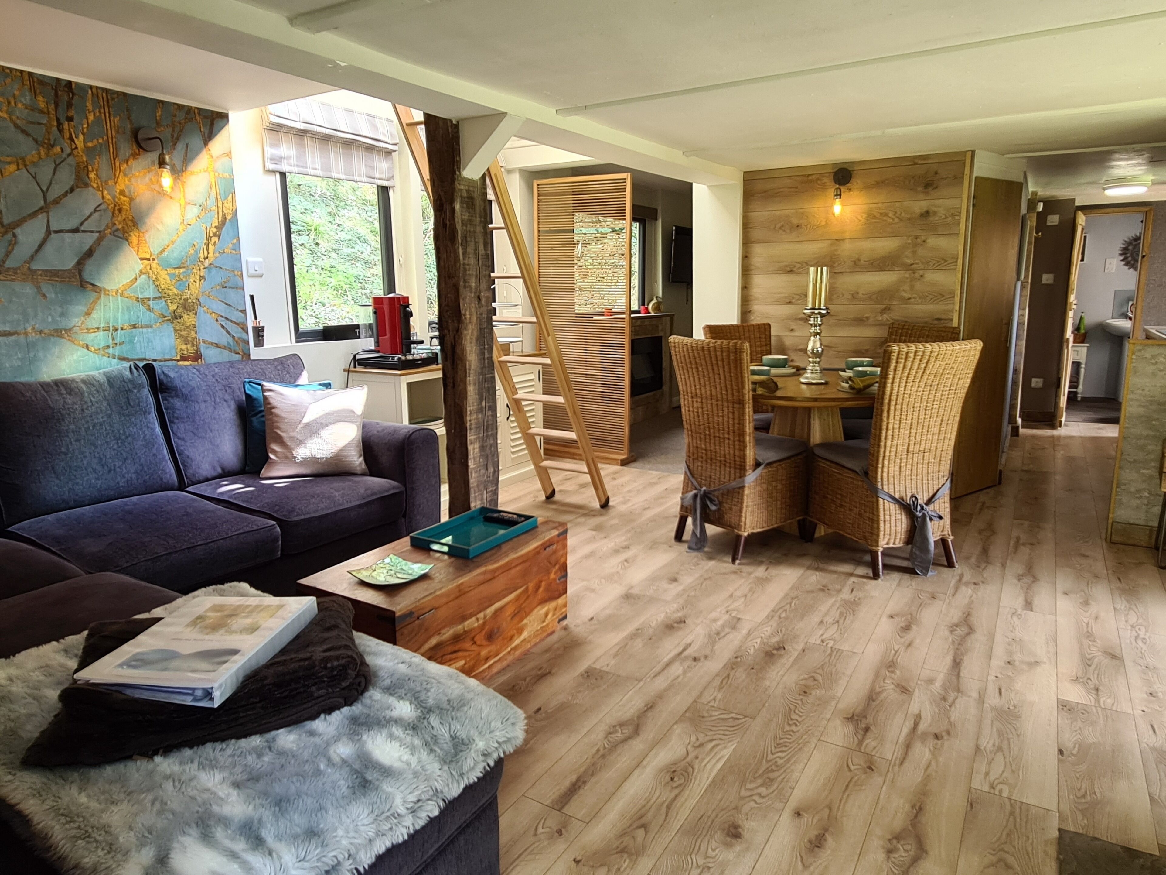 Ein modernes Wohnzimmer mit einer Couch, einem Couchtisch und Korbstühlen. Eine Treppe führt zu einer oberen Ebene.