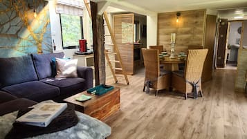 Ein modernes Wohnzimmer mit einer Couch, einem Couchtisch und Korbstühlen. Eine Treppe führt zu einer oberen Ebene.