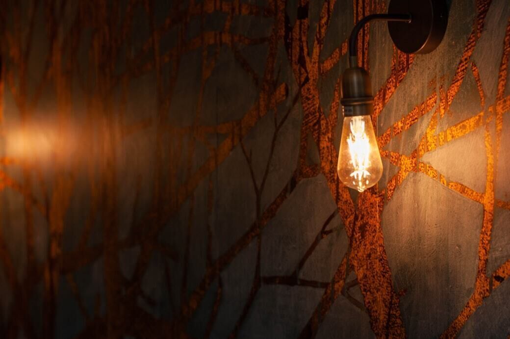 Un luminaire mural doté d’une ampoule à filament apparent.