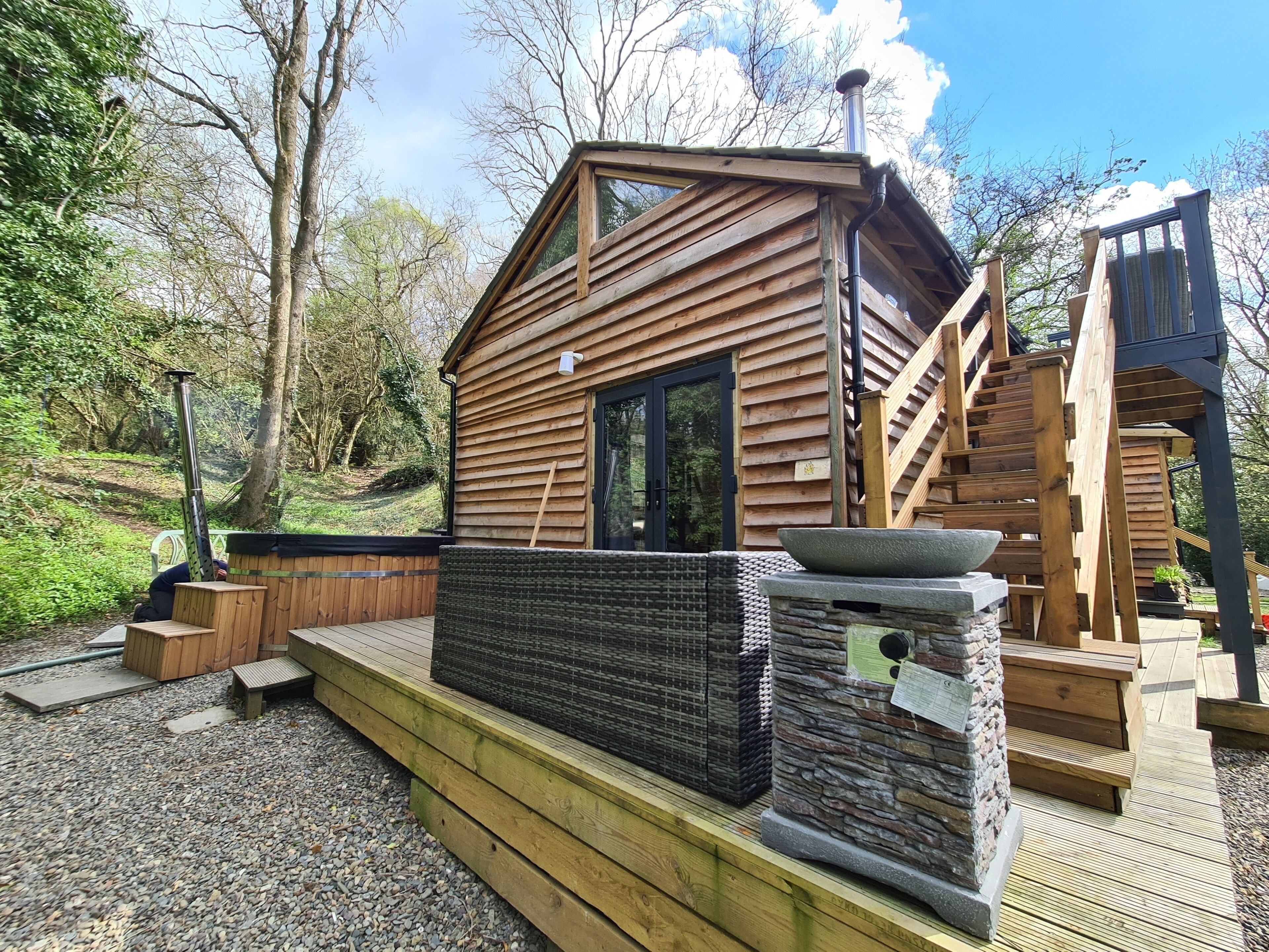 Eine Holzhütte mit einem großen Fenster, einem Steinkamin und einer Holzterrasse.