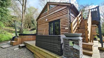 Eine Holzhütte mit einem großen Fenster, einem Steinkamin und einer Holzterrasse.