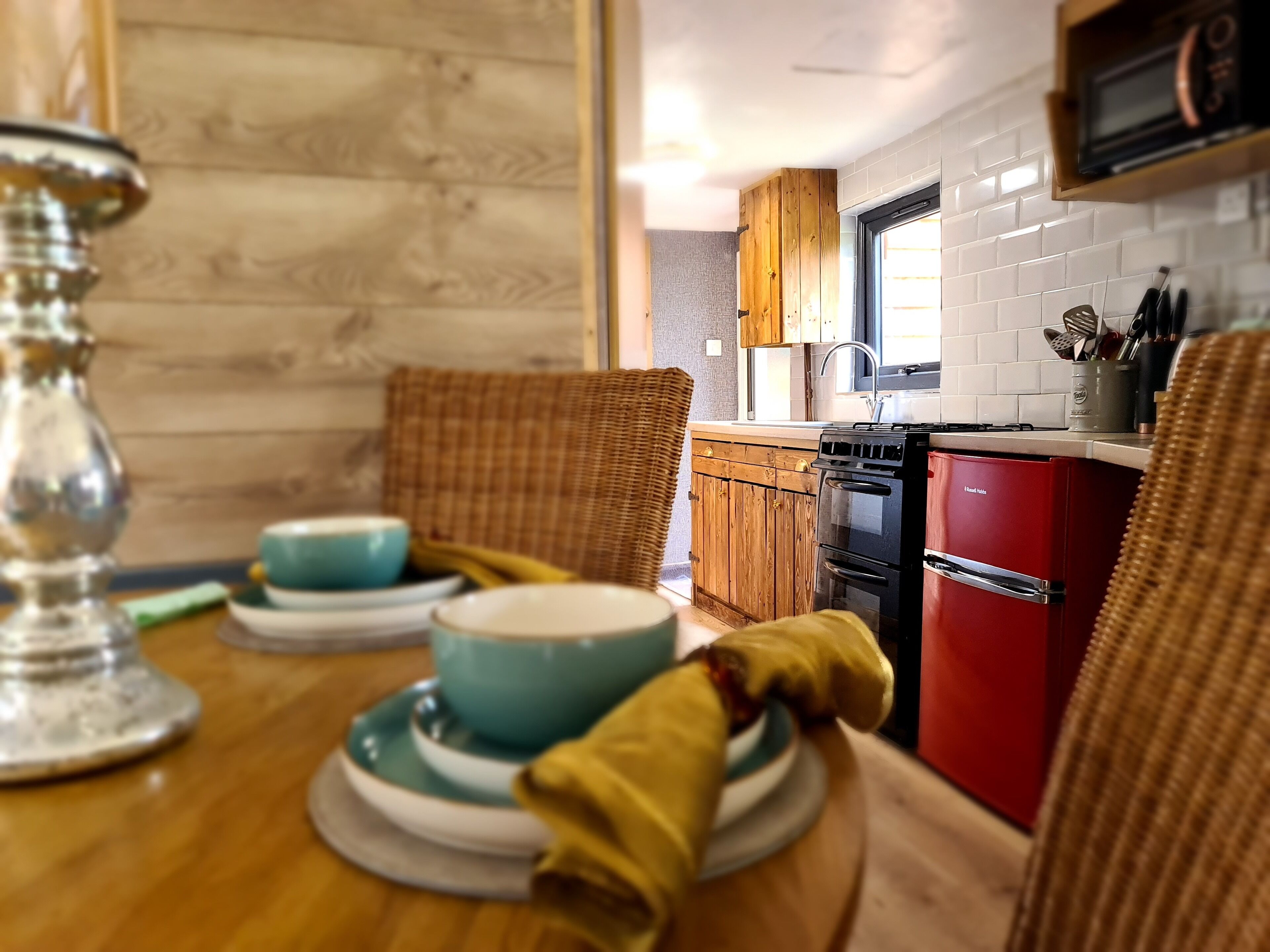 Una cocina funcional con armarios de madera, un refrigerador rojo y un microondas.