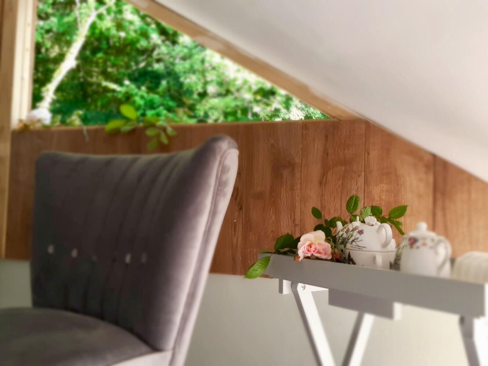 Una habitación moderna con una butaca tapizada de gris, una mesa blanca y una pared de madera.