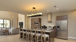 A modern kitchen with a central island, stainless steel appliances, and a dining area with chairs.