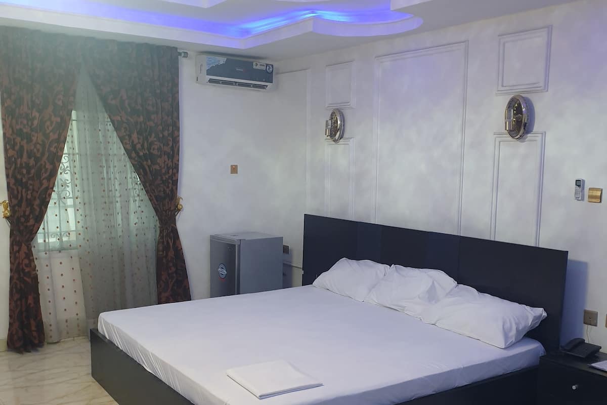 Un dormitorio con cama, mesita de noche, equipo de aire acondicionado y lámpara en el techo.