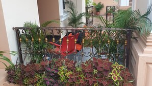 Un balcon avec une balustrade en métal, des plantes en pot et une chaise rouge.