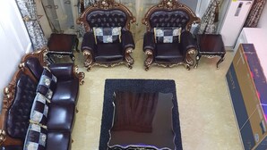 Un salon luxueux, agrémenté de meubles richement décorés, notamment deux fauteuils et un canapé, une table basse centrale et un miroir décoratif.