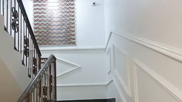 A staircase with alternating black and beige steps, a metal railing with decorative elements, and a window with patterned blinds.