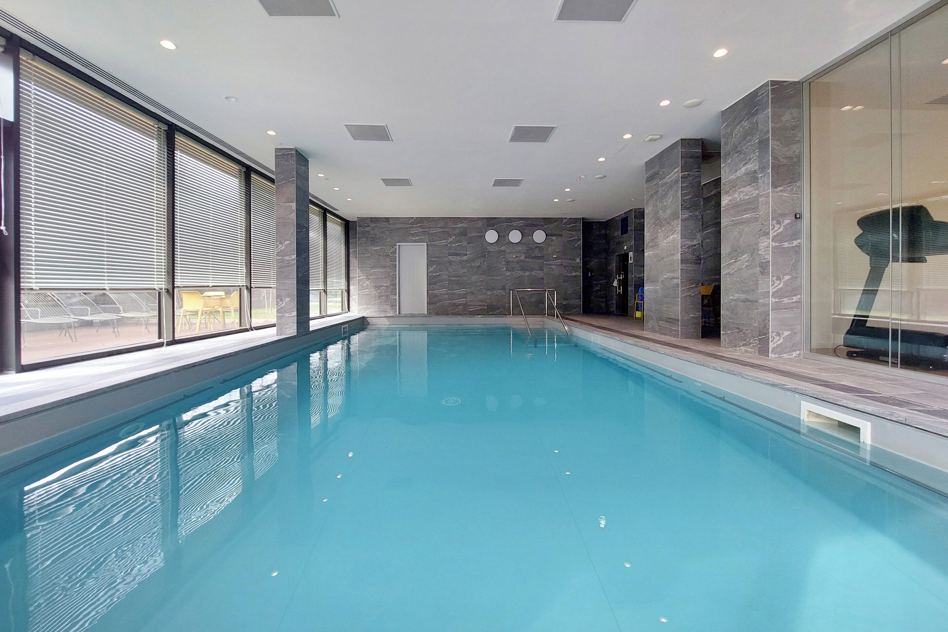 Una piscina coperta con vista diretta sull'area della piscina, ampie finestre e un design d'interni moderno.