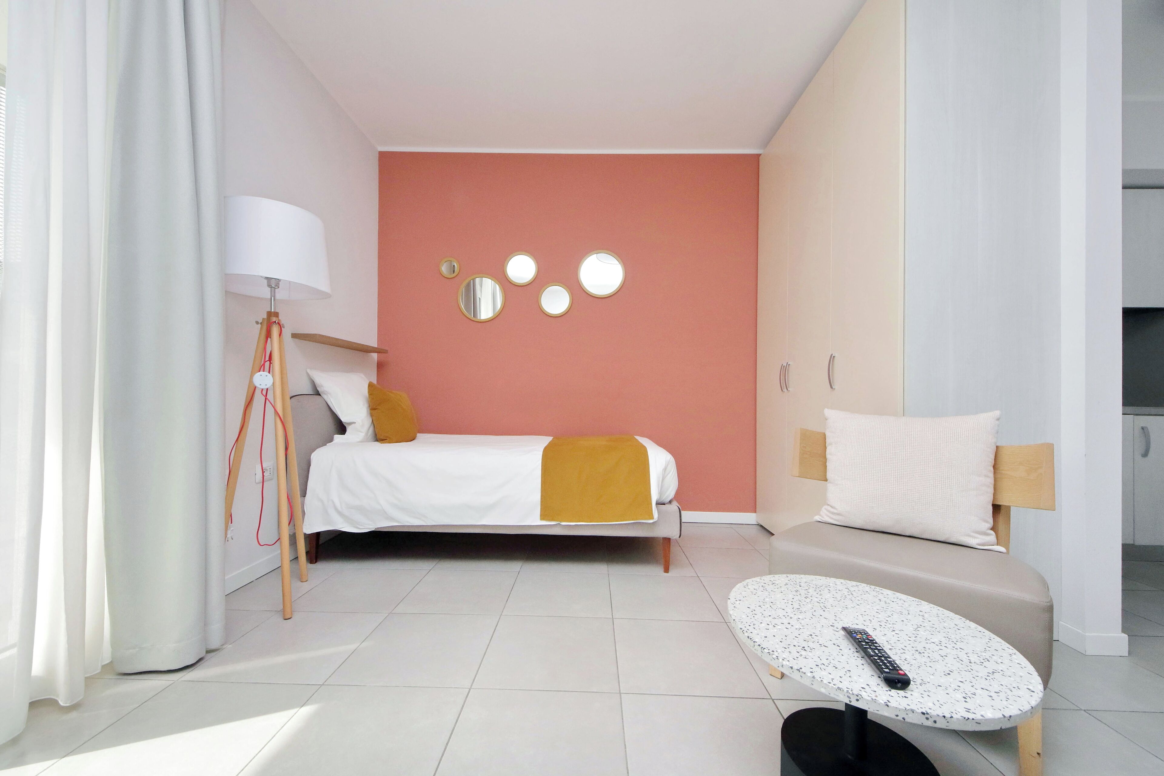 Et moderne hotelværelse med seng, sofa, lille bord, lampe og billeder på væggen.